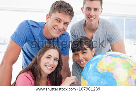 A group of people smiling as they all look into the camera with a globe next to them