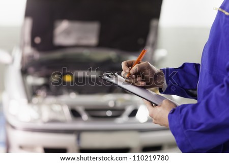 Closeup of a man writing on a clipboard in a garage