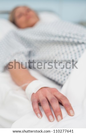 Focus on the hand of a patient lied on a bed in hospital ward