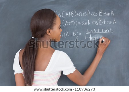 Black student writing on a blackboard in a classroom