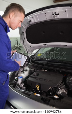 Mechanic testing the engine with a tablet computer in a garage