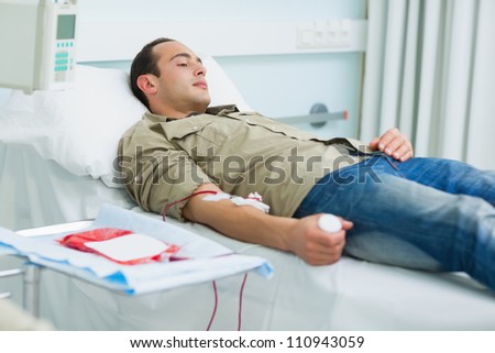 Transfused patient lying on a bed in hospital ward