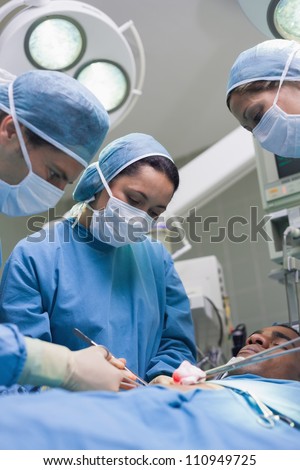 Doctors operating with surgical tools in operating theater