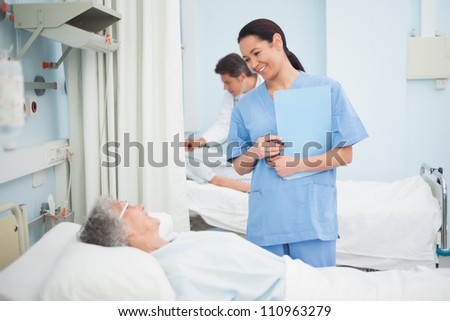 Nurse smiling to a patient in hospital ward