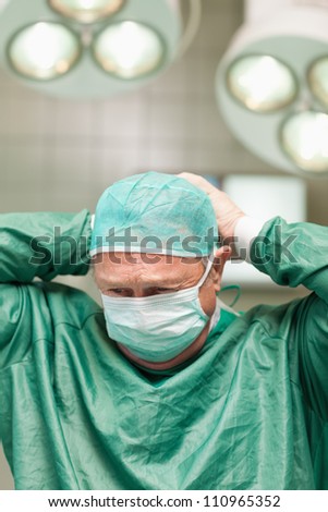 Surgeon putting on a face mask on his head in a surgical room
