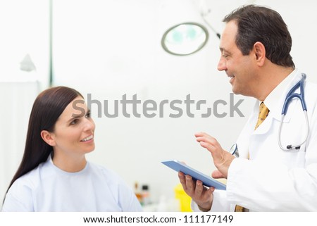 Doctor talking to a patient while holding a tablet tactile in an examination room
