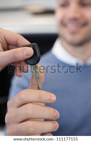 man holding a car key in a car shop