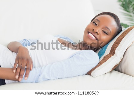 Black woman lying on back on a sofa in a living room