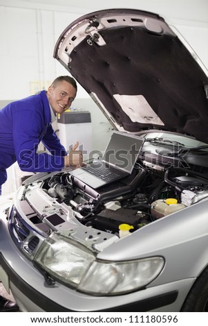 Mechanic repairing a car with a computer in a garage