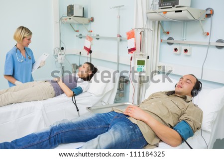 Patients lying on beds in hospital ward