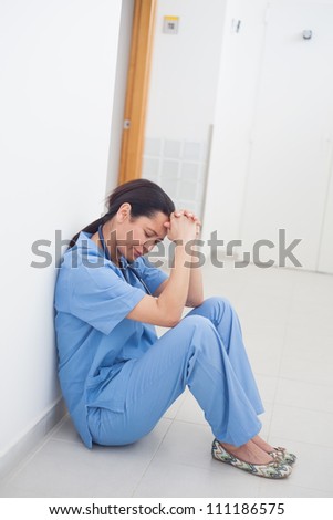 Sad nurse sitting on the floor in hospital ward