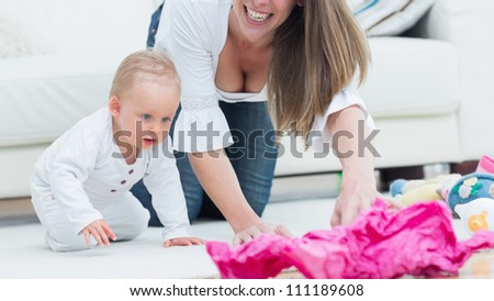 Baby and a mother on all fours in living room