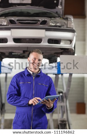 Mechanic touching a tablet computer while looking at camera in a garage