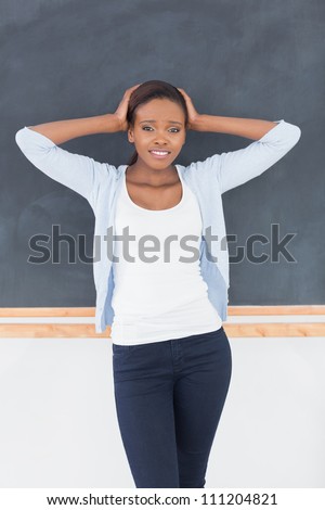 Black woman upset next to a blackboard in a classroom
