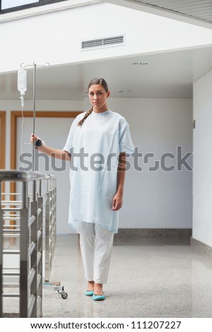 Patient walking with a drip stand in hospital hallway