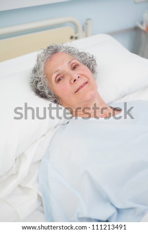 Patient looking at camera on a bed in hospital ward