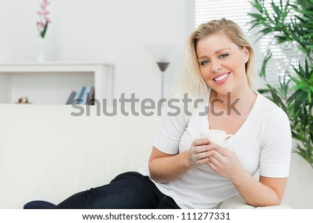 Woman seating on a sofa with a cup in a lounge