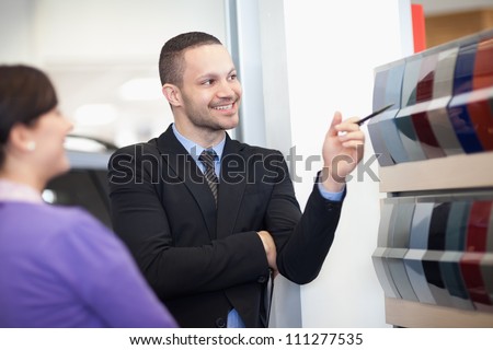 Smiling salesman pointing at a color palette with a woman