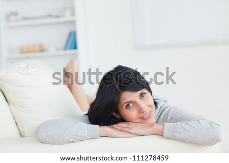 Woman resting on a sofa while resting her head on her arms in a living room