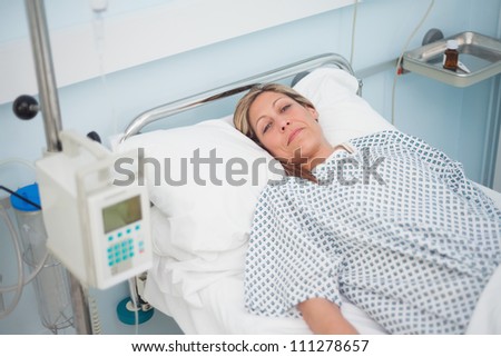 Female patient lying on a bed while looking at camera in hospital ward