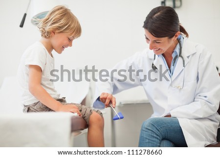 Doctor testing reaction of a child leg in examination room