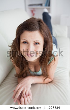 Smiling woman lying on the belly on a sofa in a living room
