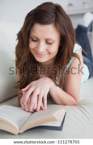 Woman lying on the belly while reading in a living room
