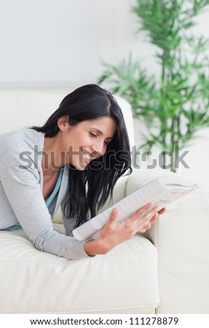 Woman smiling while she reads a magazine in a living room