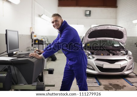 Smiling mechanic using a computer in a garage