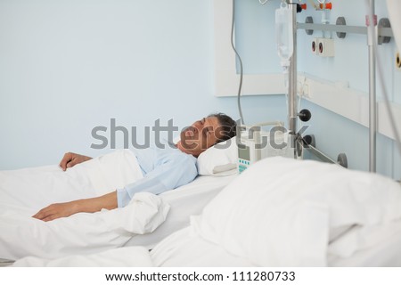 Male patient lying on a medical bed in hospital ward