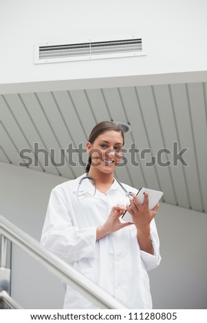 Smiling female doctor using a tablet computer in hospital stairs
