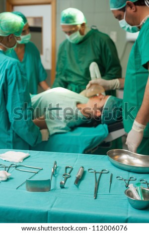 Surgery trolley with surgical tools in front of a medical team in a surgical room