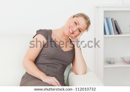 Woman sitting on a sofa while holding her head with her hand in a lounge