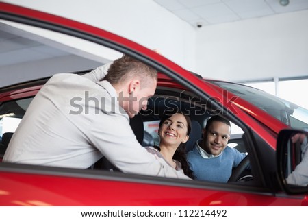 Couple in a car listening to a salesman in a car shop