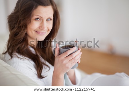 Woman smiling while holding a coffee mug in a living room
