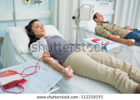 Two transfused patients lying on a bed in hospital ward