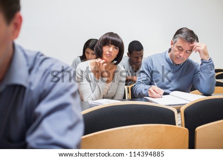 Students sitting in the adult class and thinking while taking notes
