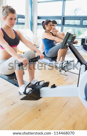 Man and womenusing the row machines in fitness studio