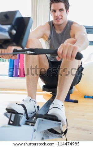 Man working out on row machine in fitness studio