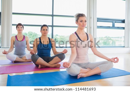 Women meditating in easy yoga pose in fitness studio