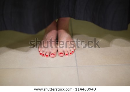 Womans feet behind changing room curtain in shopping mall