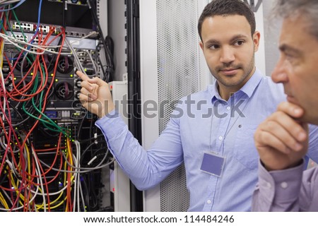 Two technicians looking at wiring of servers in data center