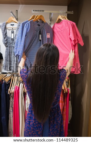 Woman looking through clothes rail in shopping mall