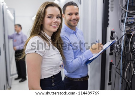 Two smiling  technicians checking the servers in data center