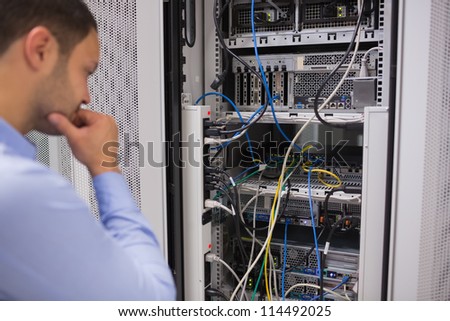 Man looking at rack mounted servers in data centre