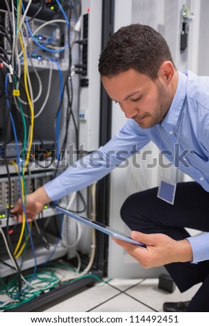 Man using tablet pc to work on servers in data center