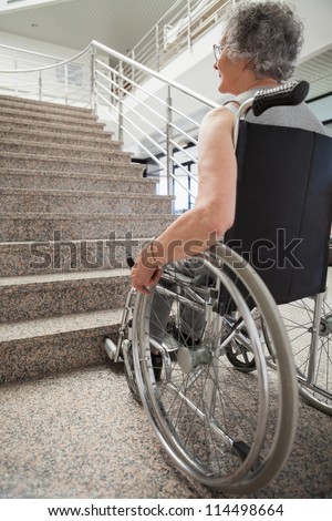 Elderly lady in wheelchair looking up hospital stairs