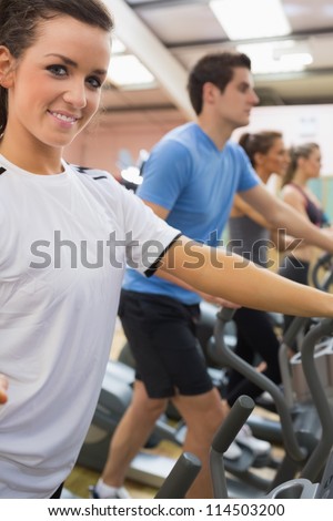 Smiling woman with other people stepping on  step machines in gym