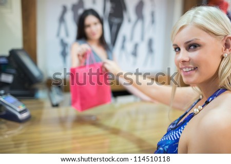 Woman taking purchases at chas register in clothing store