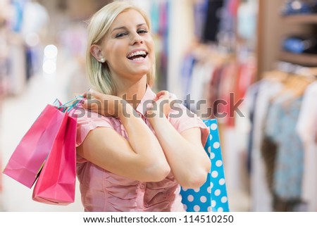 Woman holding two bags laughing in clothes shop